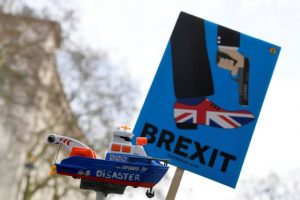 FILE PHOTO: Anti-Brexit protesters hold up a sign and a model prop boat outside Downing Street in London - TA NEA - TA NEA