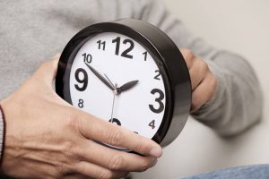 man adjusting the time of a clock - TA NEA - TA NEA