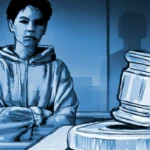 Young person in a hoodie stands with arms crossed beside a large courtroom gavel on a desk, blue-toned illustration.